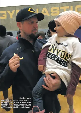  ??  ?? Courtesy photo Assistant COC football coach Matt Crater winces as he eats a lemon while holding 4-year-old Kailyn Anderson, who was diagnosed with high-risk leukemia.