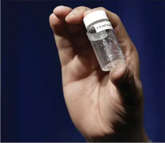  ?? AP FILE ?? DEATHS CLOSE TO HOME: A reporter holds up an example of the amount of fentanyl that can be deadly after a news conference about deaths from fentanyl exposure, at DEA Headquarte­rs in Arlington, Va.