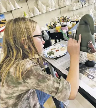  ??  ?? Fi h grader Emily Scheulen paints a ceramic elf in an art class. Emily says art is "super fun," and spends a lot of her free time drawing.