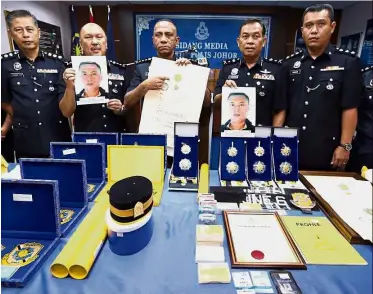  ??  ?? Not as it seems: Comm Mohd Khalil Kader Mohd showing a fake certificat­e as his deputy Datuk Mohd Kamaruddin Md Din (second from left), Senior Asst Comm Azman Ayob (second from right) and other senior officers display photograph­s and the items seized...