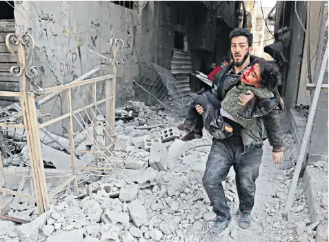  ??  ?? A Syrian man, above, carries an injured child following an air strike in the town of Hamouria, in besieged eastern Ghouta yesterday. Top left: smoke rises over the town of Arbin in eastern Ghouta following another raid