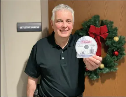  ?? PHOTO COURTESY OF BRENDAN MOORE ?? Ferndale police Detective Brendan Moore with a copy of his “Christmas in Detroit” album featuring traditiona­l, singalong holiday songs that people can get if they donate $10 to Gleaners Food Bank.
