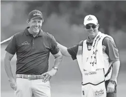  ?? JOE MAHONEY/RICHMOND TIMES-DISPATCH VIA AP ?? Phil Mickelson gets a pat on the back from Jeff Johnson, the caddie for Retief Goosen, during the final round of the Dominion Energy Charity Classic on Sunday in Richmond, Va.