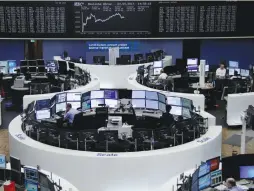  ?? (Reuters) ?? TRADERS WORK IN front of the German share price index board at the stock exchange in Frankfurt, yesterday.