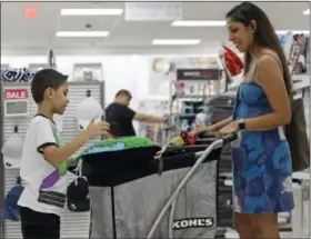  ?? THE ASSOCIATED PRESS ?? Luke Vega, 7, left, looks in a cart with his mother Kimberly Vega, right, as they shop at a Kohl’s store in Concord, N.C.