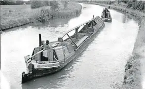  ?? PHOTO: CC-IWM. ?? Two canal boats travel the Grand Union Canal with a cargo of coal, bound for London. The second of the two (the ‘butty’) is towed behind and being steered by Valerie Gribbis, the boatman’s daughter.