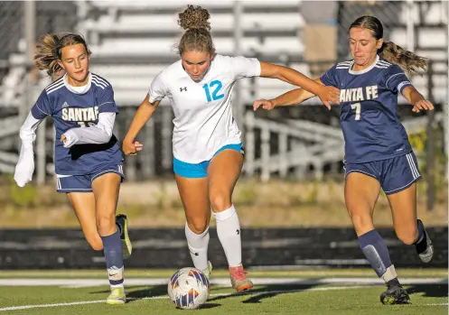  ?? PHOTOS BY LUIS SÁNCHEZ SATURNO/THE NEW MEXICAN ?? Santa Fe High’s Meliya Gharrity, left, and Lily Earnest, right, go after Cleveland’s Sienna Salazar during the first half of Monday’s match at Santa Fe High.