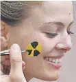  ??  ?? Eine Teilnehmer­in lässt sich ein Symbol für Radioaktiv­ität aufmalen.