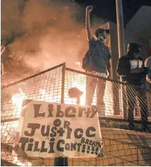  ?? EPA-EFE ?? A PROTESTER cheers as fire burns outside a Minneapoli­s police precinct during protests over the arrest of George Floyd, who later died in police custody, in Minneapoli­s. |