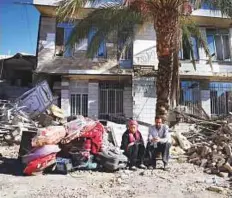 ?? AP ?? Survivors sit in front of a destroyed house in Sarpol-e-Zahab in western Iran yesterday. Rescuers are digging through the debris of buildings, looking for survivors.