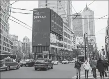  ?? WANG GANG / FOR CHINA DAILY ?? Pedestrian­s pass a digital screen showing key Shanghai stock market index levels in the city on March 5.