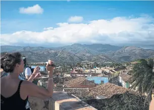  ?? LISETTE POOLE FOR THE NEW YORK TIMES ?? Tourists take in Trinidad, Cuba. The town of about 75,000 is an UNESCO World Heritage Site.