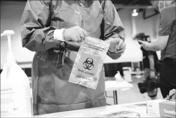  ?? CHRISTOPHE­R DEVARGAS (2020) ?? Diane Vega, a respirator­y therapist at UMC, processes sealed COVID-19 tests in August 2020 at the Cashman Center testing facility in Las Vegas. Nevada’s experience with farming out test results to a lab in Chicago when the delta and omicron variants of the coronaviru­s were breaking out in 2021 uncovered a lapse in the U.S. public health administra­tion: The lack of national standards for ongoing verificati­on of lab results.