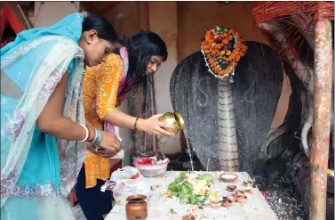  ?? IANS ?? Devotees offer prayers to the idol of a naga (snake) at a temple on the occasion of Naga Panchami, in Patna on Saturday.