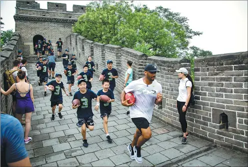  ?? PROVIDED TO CHINA DAILY ?? Super Bowl-winning quarterbac­k Russell Wilson of the Seattle Seahawks jogs on the Great Wall with a group of kids in tow on Tuesday. The 28-year-old is on a weeklong visit to China to promote American football.