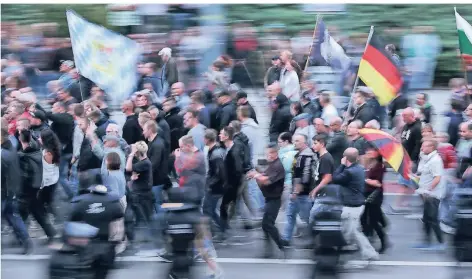  ?? FOTO: DPA ?? Demonstran­ten der rechten Szene schwenken in Chemnitz Deutschlan­dfahnen und tragen einen Regenschir­m in Deutschlan­dfarben.