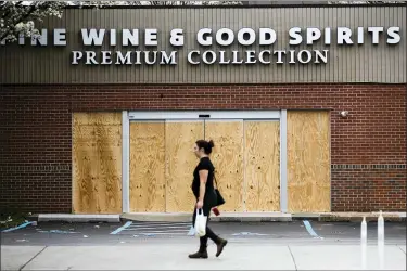  ?? MATT ROURKE — THE ASSOCIATED PRESS ?? A pedestrian walks past a boarded up Wine and Spirits store in Philadelph­ia, Friday, March 20, 2020. Pennsylvan­ia Gov. Tom Wolf directed all “non-life-sustaining” businesses to close their physical locations late Thursday and said state government would begin to enforce the edict starting early Saturday.