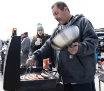  ?? ?? Jason Caprigno of Elk Grove Village grills sausages Thursday at his tailgate spot.