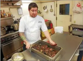  ?? VIRGINIA LINDAK — FOR DIGITAL FIRST MEDIA ?? Chef Seth Williams takes the main course out of the oven at the annual Camphill Village Kimberton Hills “What’s For Dinner?” fundraiser.