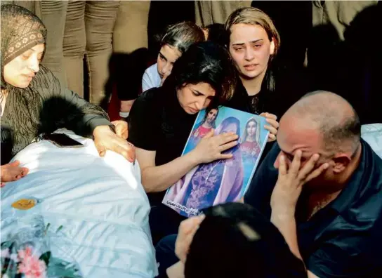  ?? ZAID AL-OBEIDI/AFP VIA GETTY IMAGES ?? Above, mourners attended the funeral of victims who were killed in the fire in Qaraqosh in Hamdaniya, Iraq, on Wednesday. At left, a video showed people gathered at the site of the fire.