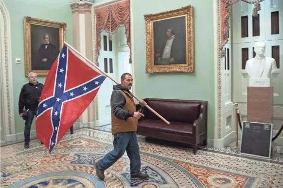  ?? SAUL LOEB/AFP VIA GETTY IMAGES ?? A supporter of President Donald Trump carries a Confederat­e flag into the U.S. Capitol Wednesday in Washington, D.C.