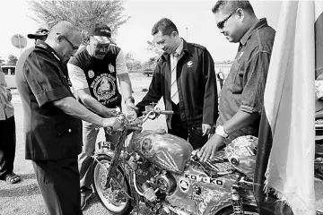  ??  ?? Kedah Road Transport Department director Isma Suhaimi Shariff (second right) checking Hishamuddi­n’s motorcycle in Alor Setar. — Bernama photo