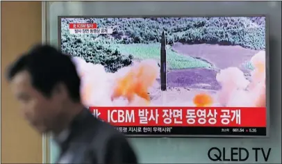  ?? The Associated Press ?? ICBM LAUNCH: A man walks by a TV screen showing a local news program reporting about North Korea's missile firing Wednesday at Seoul Train Station in Seoul, South Korea. North Korea’s newly demonstrat­ed missile muscle puts Alaska within range of...