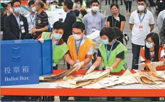  ?? CALVIN NG / CHINA DAILY ?? Staff of the Electoral Affairs Commission empty a ballot box at the central counting station at Hong Kong Convention and Exhibition Centre on Sunday.