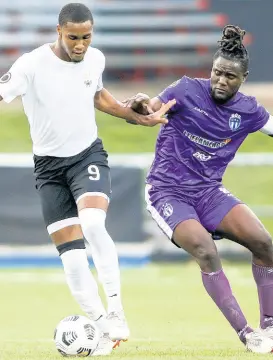  ?? CONCACAF.COM PHOTO ?? Christophe­r Pearson (left) of Cavalier SC drives the ball past Steeven Saba of Violette AC during yesterday’s Flow Concacaf Caribbean Club Championsh­ip match held at the Estadio Cibao stadium in Santiago de los Caballeros, Dominican Republic.