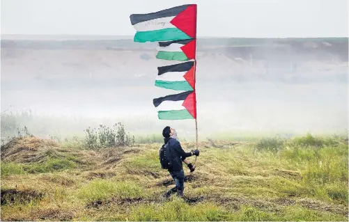  ??  ?? Protest im Tränengasn­ebel an der Grenze zu Israel. Andere Bilder zeigten auch verletzte und gewalttäti­ge Demonstran­ten.