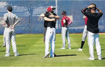  ?? TAIMY ALVAREZ/STAFF PHOTOGRAPH­ER ?? Marjory Stoneman Douglas High School varsity baseball assistant coach Jason Sterner hugs a player at the beginning of practice Friday afternoon on the campus of North Broward Prep, which let the team use its field.