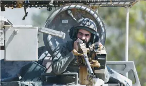  ?? (Amir Cohen/Reuters) ?? AN IDF soldier on a military vehicle near the Gaza border last week; The low ratio of civilian-tocombatan­t deaths is noteworthy as the war is fought in dense urban areas where civilians have little protection, and Hamas fighters are protected in undergroun­d tunnels, says the writer.