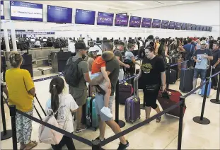  ?? Associated Press ?? Stranded tourists line up in front of the Thomas Cook counter at the Cancun airport in Mexico on Monday. British tour company Thomas Cook collapsed early Monday after failing to secure emergency funding, leaving tens of thousands of vacationer­s stranded abroad.