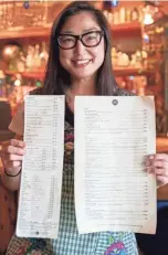  ?? ?? Mindy Son holds the Do Sushi original menus at Bar DKDC in Memphis. The general manager, Son will help roll sushi during the pop-up.