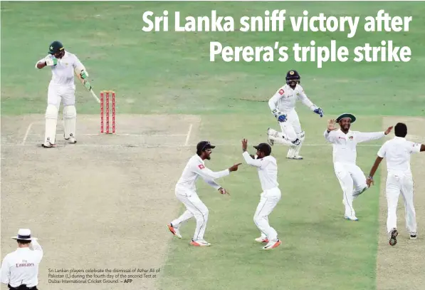  ?? — AFP ?? Sri Lankan players celebrate the dismissal of Azhar Ali of Pakistan (L) during the fourth day of the second Test at Dubai Internatio­nal Cricket Ground.