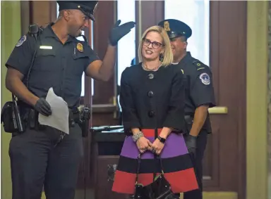  ??  ?? Sen.-elect Kyrsten Sinema, D-Ariz., gets direction from a Capitol Police officer upon entering the Senate carriage entrance of the Capitol on Wednesday in Washington. TOM WILLIAMS/AP