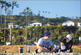  ?? Francine Orr Los Angeles Times ?? GLENDALE family Ibrahim Alkadi, 32, Lina Aleidi, 29, and 1-year-old Youself bask in the sun on Sunday at Will Rogers State Beach in Pacific Palisades.