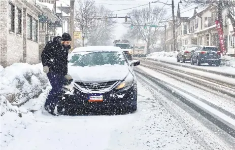  ?? PHOTOS BY MONICA CABRERA/THE MORNING CALL ?? A man wipes snow from his headlights on a snowy morning on Main Street in Hellertown. The borough got 4.3 inches of snow, a trained spotter reported to the National Weather Service.