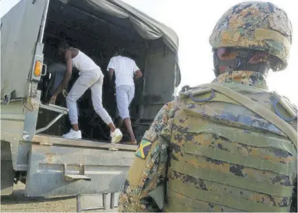  ??  ?? Two men detained under the state of public emergency enter a Jamaica Defence Force lorry under he watchful gaze of a soldier. The Office of the Public Defender has charged that no arrangemen­t was put in place for the handling of detainees prior to the launch of the security measure in St James in January last. year.