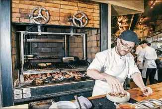  ?? VINCENT TULLO/THE NEW YORK TIMES ?? John Sobojinski cooks on a wood-burning grill at Lilia, a restaurant in New York. High-end chefs and home cooks alike are forsaking gas and charcoal for the intense heat and fragrant smoke of a traditiona­l wood fire.