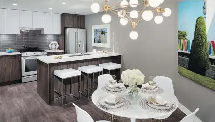  ??  ?? This show suite kitchen was fitted with dark flooring and cabinetry, offset by white kitchen island seat cushions and a bright white table and chairs.