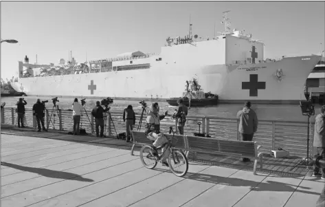  ?? PHOTO MARK J. TERRILL ?? In this Friday photo, a cyclist rides by the US Naval Ship Mercy enters the Port of Los Angeles. The 1,000bed USNS Mercy (T-AH 19) docked at the Port of Los Angeles accepted its first patients Sunday during its support of the nation’s COVID-19 response efforts.