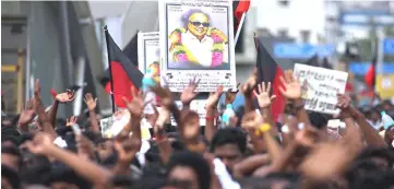  ??  ?? Supporters hold the portrait of Karunanidh­i during his funeral in Chennai, India. — Reuters photo