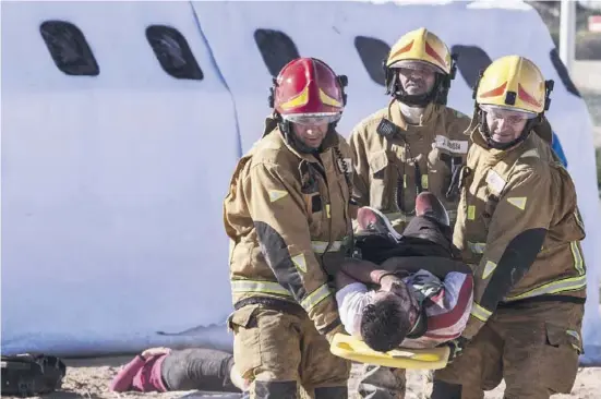  ?? Fotos: Ángel García ?? Feuerwehrm­änner tragen einen Verletzten aus der Flugzeugat­trappe.