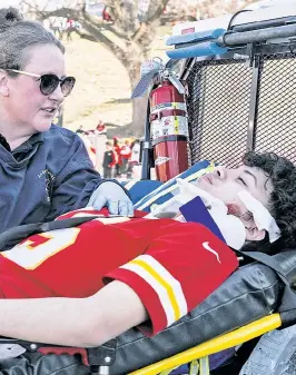  ?? ?? BRAVERY IN ACTION: A wounded youth is treated by a first responder Wednesday after bullets flew at a parade to honor the Super Bowl victory of the Kansas City Chiefs, sending fans running and leaving one woman dead and 22 others wounded — including nine kids. Police have three suspects in custody, two of whom are minors, and have ruled out domestic extremism as motive for the shooting.