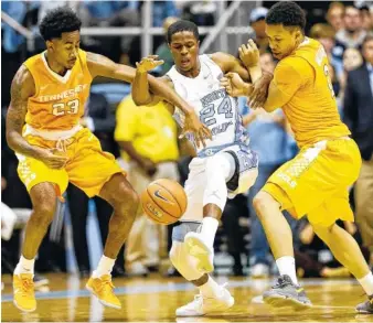  ?? FILE PHOTO BY THE ASSOCIATED PRESS ?? North Carolina’s Kenny Williams, center, gets tangled up with Tennessee’s Jordan Bowden, left, and Grant Williams during their game last December in Chapel Hill. The Tar Heels will complete a home-and-home set by visiting the Vols on Dec. 17 this season.