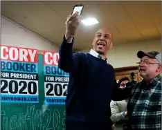  ?? AP Photo/chArlIe NeIbergAll ?? U.S. Sen. Cory Booker, D-N.J., poses for a photo with Chris Peterson, of Clear Lake, Iowa, (right) during a meet and greet with local residents at the First Congregati­onal United Church of Christ, on Friday in Mason City, Iowa.