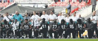  ?? Matthew Lewis, Getty Images ?? Jacksonvil­le Jaguars players and staff members show their unity during the national anthem before their game Sunday against the Baltimore Ravens at Wembley Stadium in London.