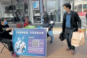  ?? Ng Han Guan, The Associated Press ?? A shopper walks past a stand this month in Beijing offering free tickets to tourist sites as part of its campaign to encourage coronaviru­s vaccinatio­ns. The sign reads, “Timely vaccinatio­n to build the Great Wall of Immunity together.”