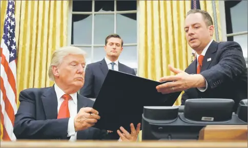  ??  ?? Trump hands Chief of Staff Reince Priebus (right) an executive order that directs agencies to ease the burden of Obamacare, after signing it in the Oval Office in Washington. Also pictured is White House Staff Secretary Rob Porter (behind). — Reuters...